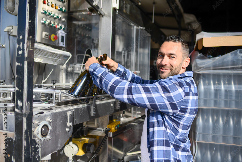 young man wine maker working filling wine bottle with automatic bottling machine