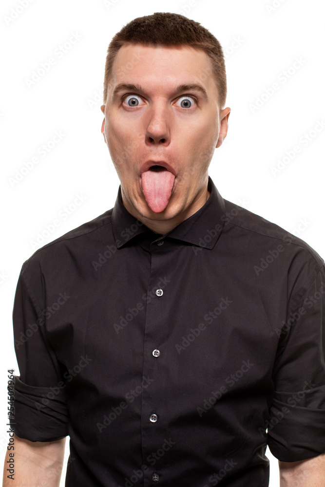Handsome young man in a black shirt is making faces, while standing isolated on a white background Handsome young man in a black shirt is making faces, while standing isolated on a white background