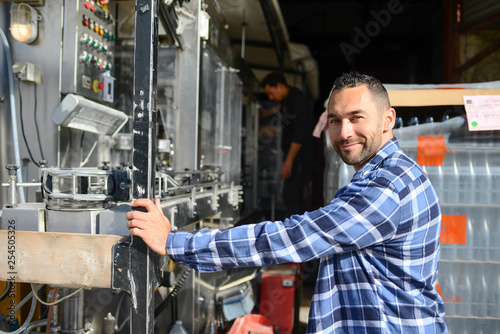 young man wine maker working filling wine bottle with automatic bottling machine