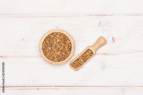 Lot of whole raw bulgur grains in a scoop with wooden bowl flatlay on white wood photo