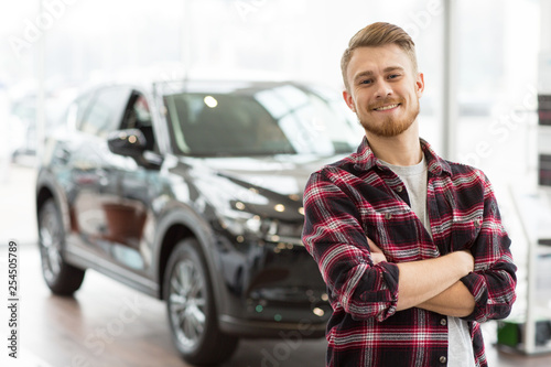 Happy handsome man buying a new car at the dealership