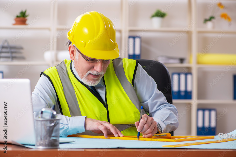 Aged construction engineer working in the office Aged construction engineer working in the office