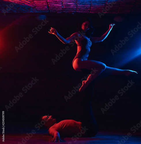 Young attractive couple dancing on the dance floor in a night club. Dancers performing in the dark with illumination © Fxquadro