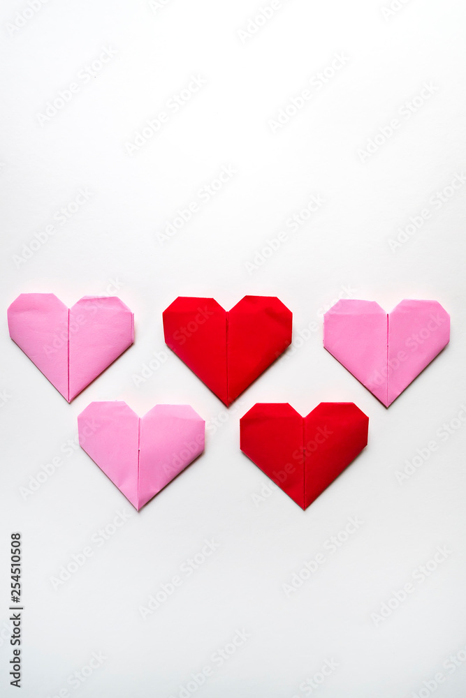 Handcraft paper red and pink hearts on a gray background with copy space for text. Creative layout for your ideas.