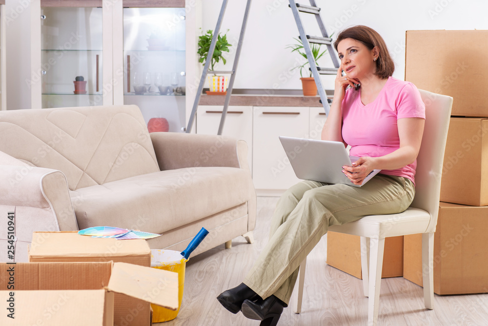 Middle-aged woman with laptop in home improvement concept Middle-aged woman with laptop in home improvement concept
