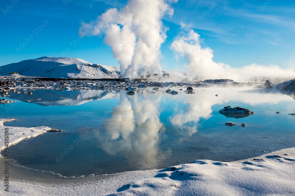 Steam from a geothermal plant set against a bright blue sky and reflected in a lake beside the Blue Lagoon - obrazy, fototapety, plakaty 