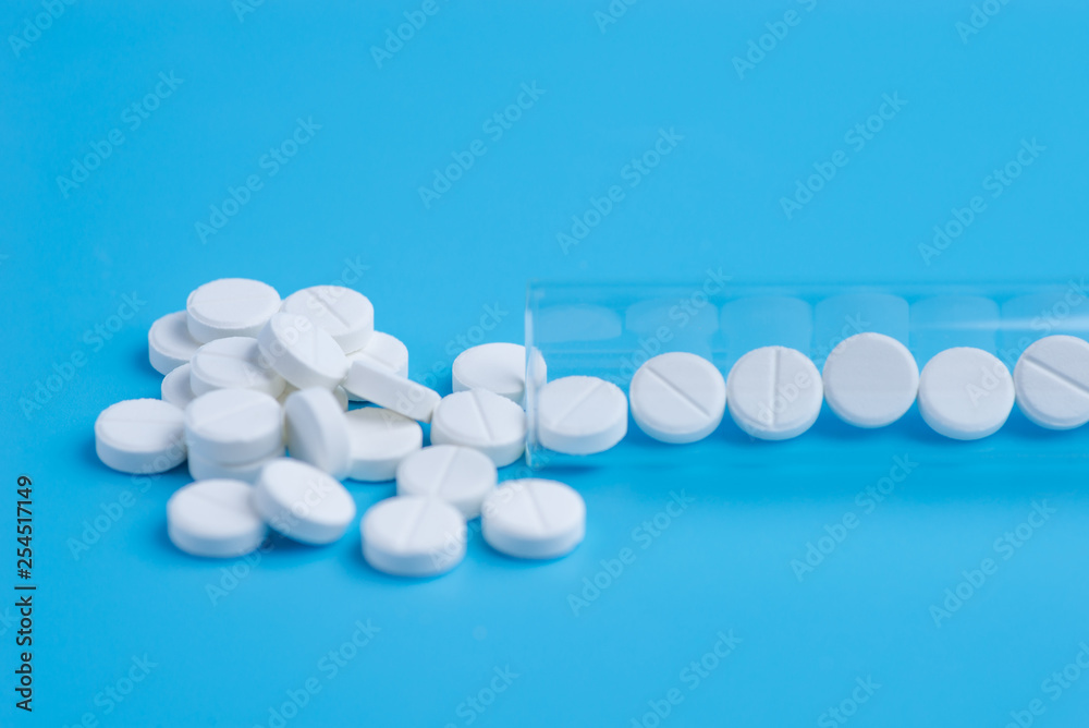 Medicine white pills in the test tube on blue background. Copy space for text