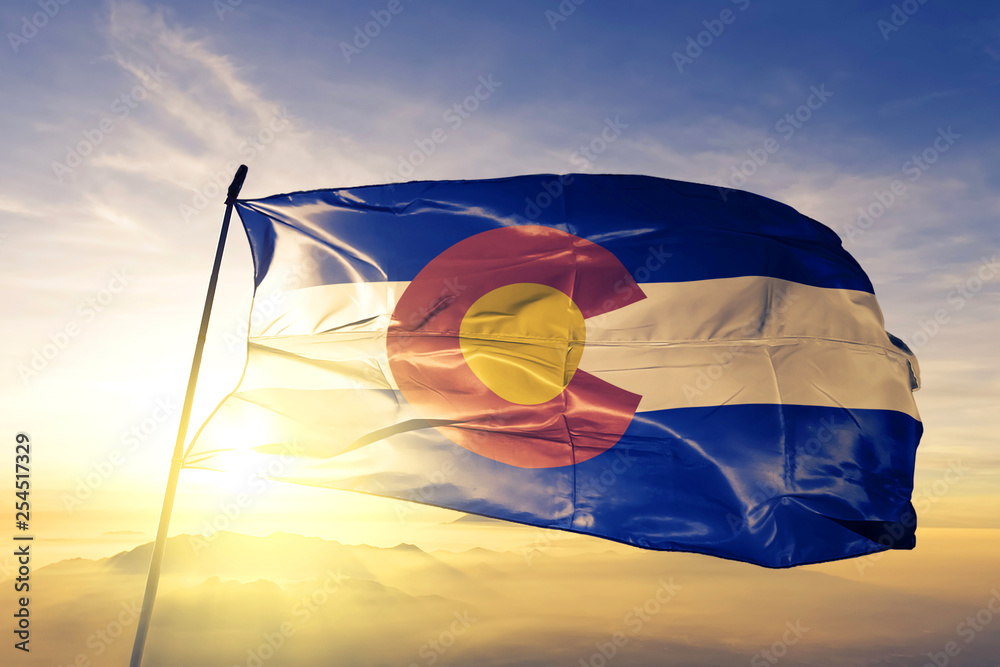 Colorado state of United States flag waving on the top sunrise mist fog - obrazy, fototapety, plakaty 