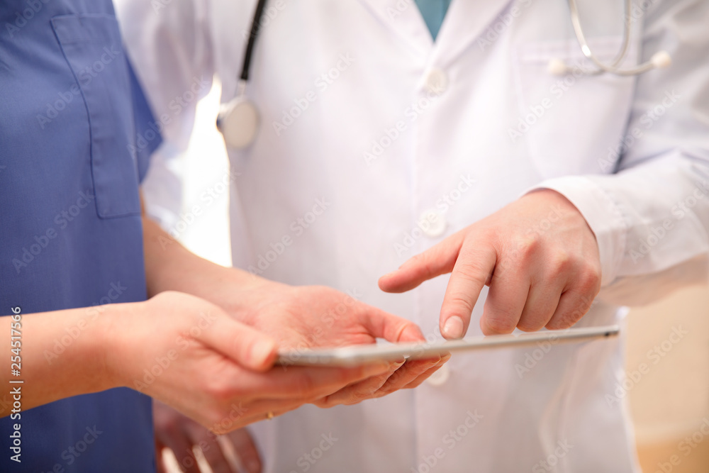 Doctor and nurse discussing patients tests at tablet computer in hospital Doctor and nurse discussing patients tests at tablet computer in hospital
