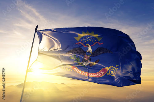 Tableau sur toile North Dakota state of United States flag waving on the top sunrise mist fog