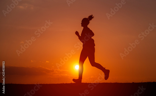 Silhouette of the running girl at sunrise.