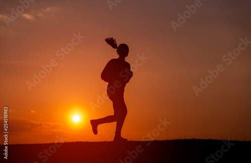 Fototapeta Naklejka Na Ścianę i Meble -  Silhouette of the running girl at sunrise.
