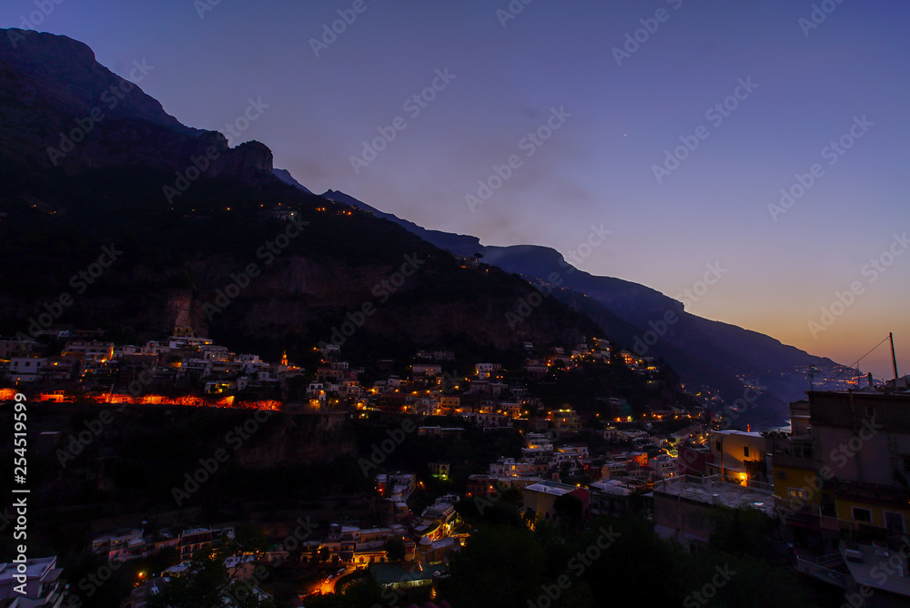 View on a city in mountains near coast. Town at the sea at dusk or night