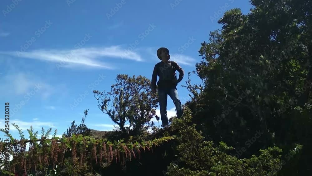 Man adventurer standing on the mountain and looking around Man adventurer standing on the mountain and looking around