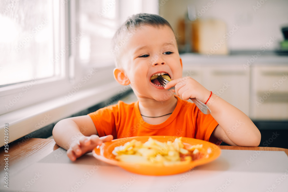 beautiful baby in orange t-shirt with orange plate eating fried French fries beautiful baby in orange t-shirt with orange plate eating fried French fries