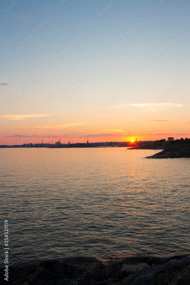 View of the Gulf of Finland at sunset of a summer day from the steep rocky shore of the island Suomenlinna Sveaborg in Finland. View from the island towards Helsinki on the horizon.