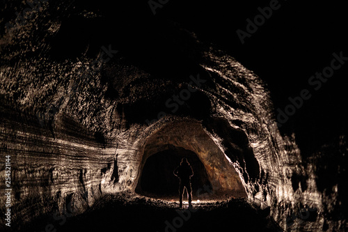 A male caver holding a propane lantern while exploring the 13,042 foot long Ape Cave near Mount St. Helens in the Gifford Pinchot National Forest of western Washington State. The cave is the third longest known lava tube in North America. The cave is open year round and has a easier, shorter lower cave section and a slightly more physical and longer upper cave section.