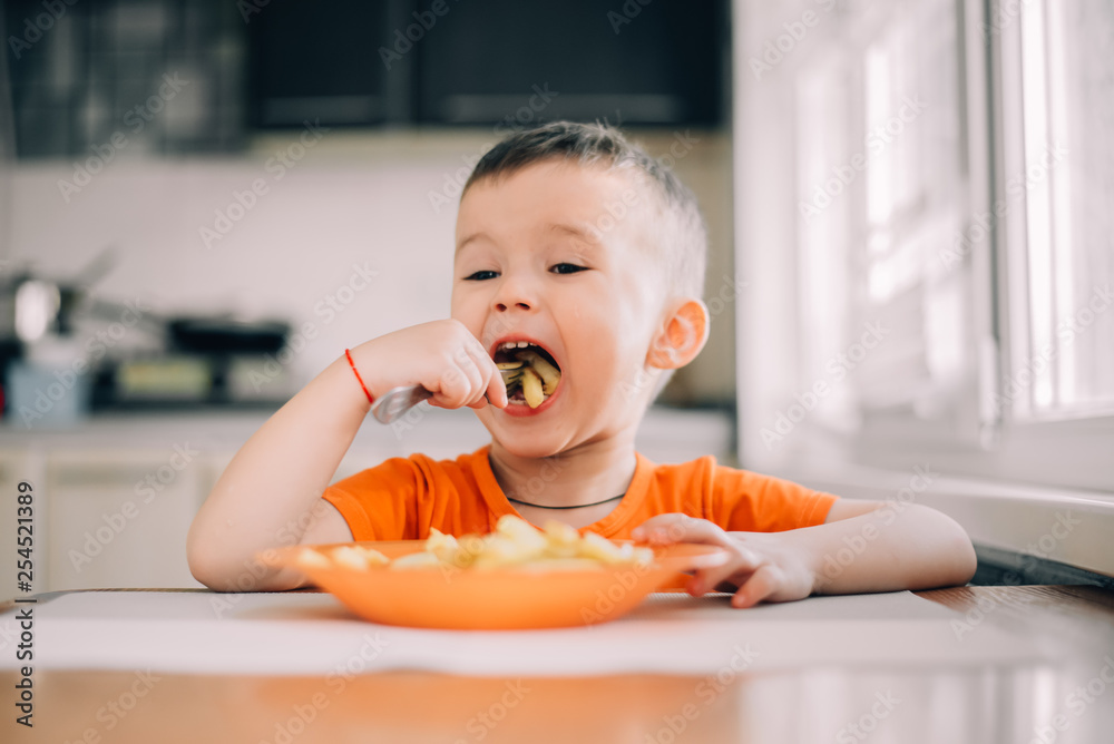 beautiful baby in orange t-shirt with orange plate eating fried French fries beautiful baby in orange t-shirt with orange plate eating fried French fries