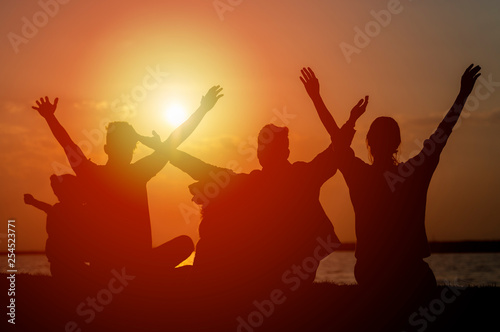 Group of teenagers and child feeling free at sunset