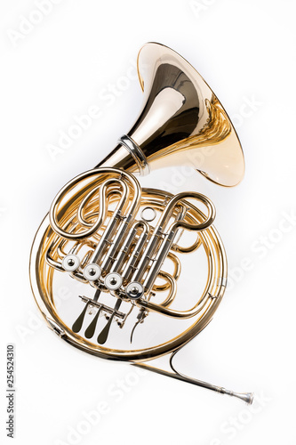 French horn on a white table. Beautiful polished musical instrument.