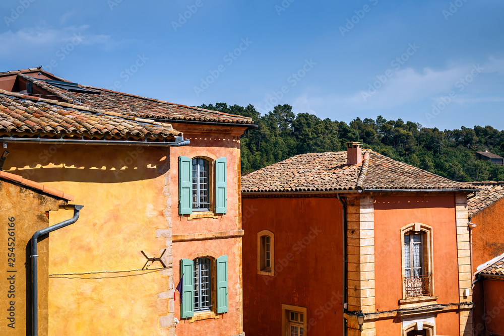 Colourful old houses, windows with shutters, multicoloured tile roofs of medieval ocher village Roussillon, Vaucluse, Provence, France.