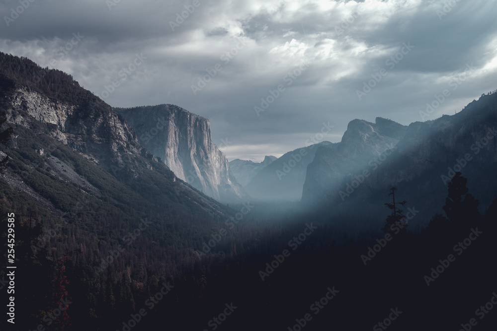 Morning sun rays pierce through the crisp autumn air, illuminating El Capitan in Yosemite Valley