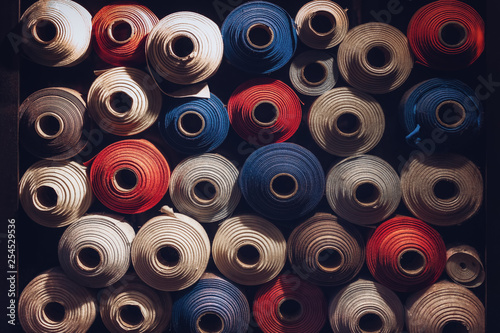 many textile rolls of blue, white and orange colors stacked one over the other in dark light