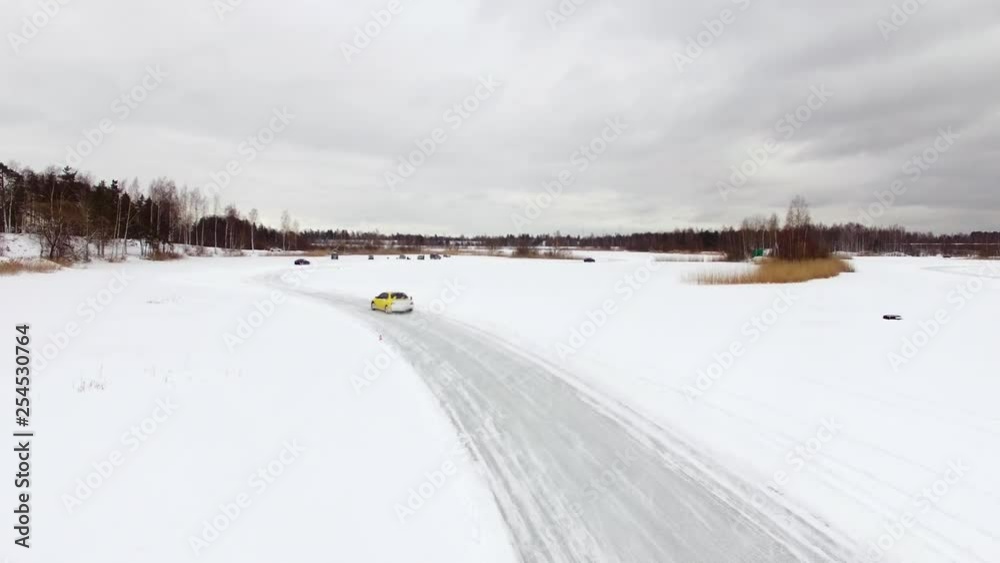 Car drives by icy track on snow covered lake at winter. Aerial view. Sport car racing on snow race track in winter. Driving a race car on a snowy road Car drives by icy track on snow covered lake at winter. Aerial view. Sport car racing on snow race track in winter. Driving a race car on a snowy road