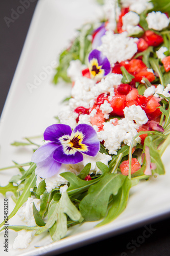 Salad made of cottage cheese, rocket salad, strawberries, pomegranates, onion decorated with flowers © teine