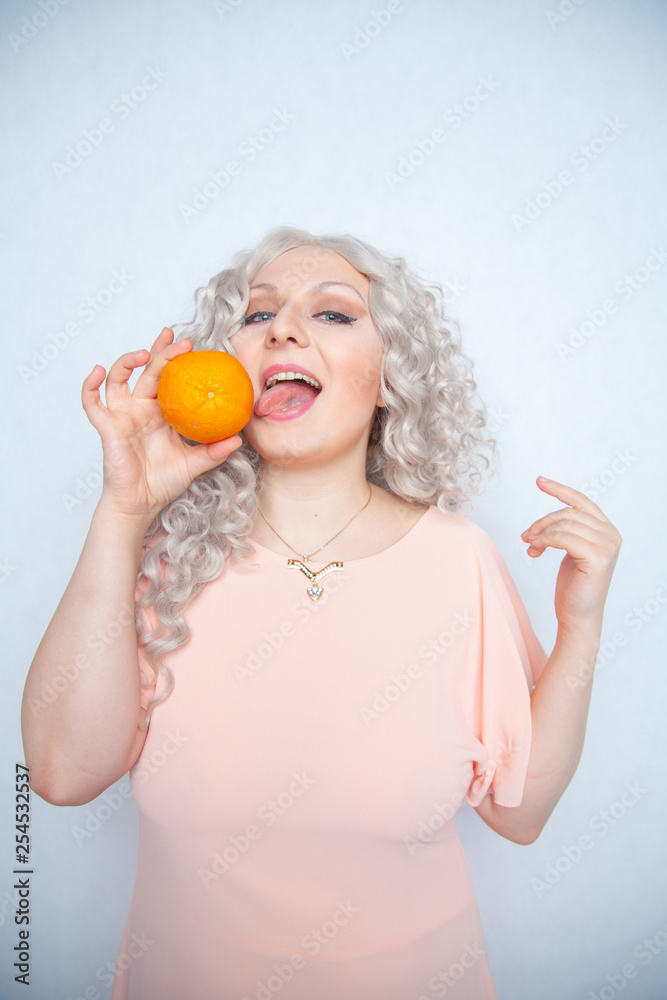charming plump curly blonde in pink dress with orange on white solid studio background alone charming plump curly blonde in pink dress with orange on white solid studio background alone