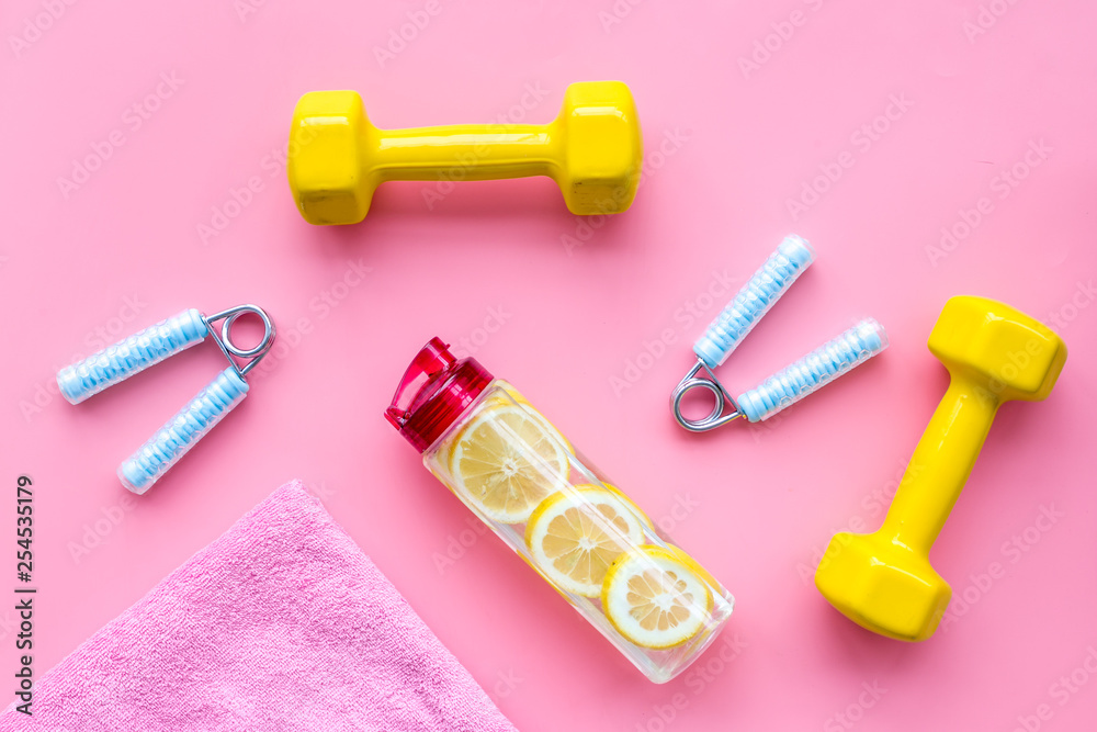 workout with bars, towel, bottle of water and wrist builder pink background top view workout with bars, towel, bottle of water and wrist builder pink background top view