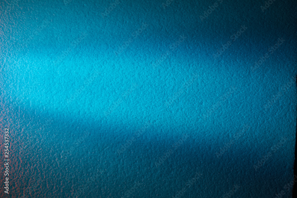 Light turquoise ray of light shines horizontally on a turquoise textural background