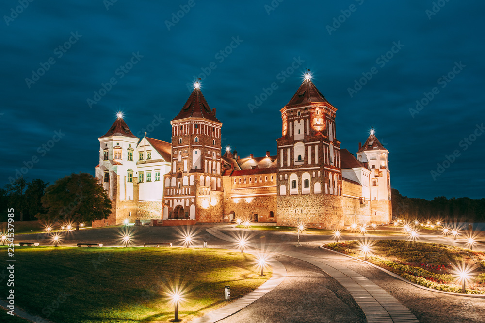 Mir, Belarus. Mir Castle Complex In Evening Illumination Lighting. Famous Landmark, Ancient Gothic Monument Of Feudalism Under Blue Night Sky. UNESCO Heritage. Architectural And Cultural Heritage