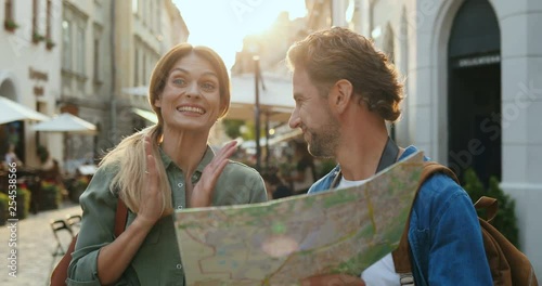 Portrait of the Caucasian cheerful romantic couple lost in the city while sightseeing and reading a map, then finding the way.