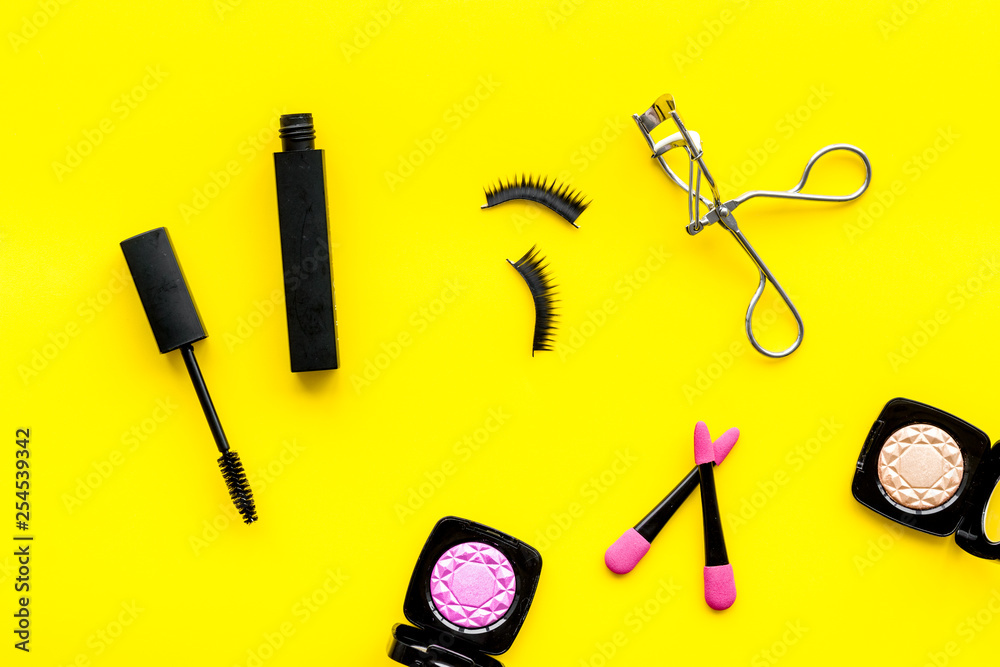 make up set with woman decorative cosmetic with eye shadows and mascara on yellow background top view