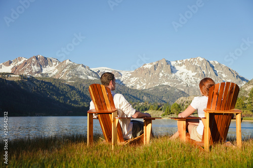 Couple in Adirondack chairs by June Lake with Sierra Nevada Mountains in distance