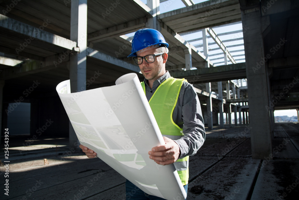 Architect looking at blueprint on construction site Architect looking at blueprint on construction site
