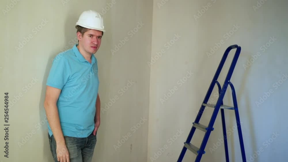 Worker at construction site renovating flat put on helmet Worker at construction site renovating flat put on helmet