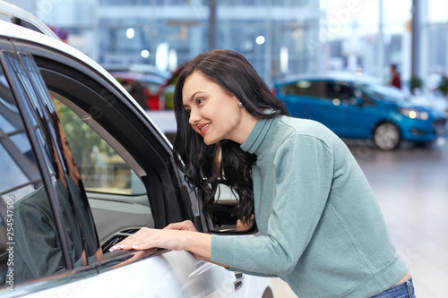 In love with this one. Portrait of a beautiful brunette woman choosing car at the car salon