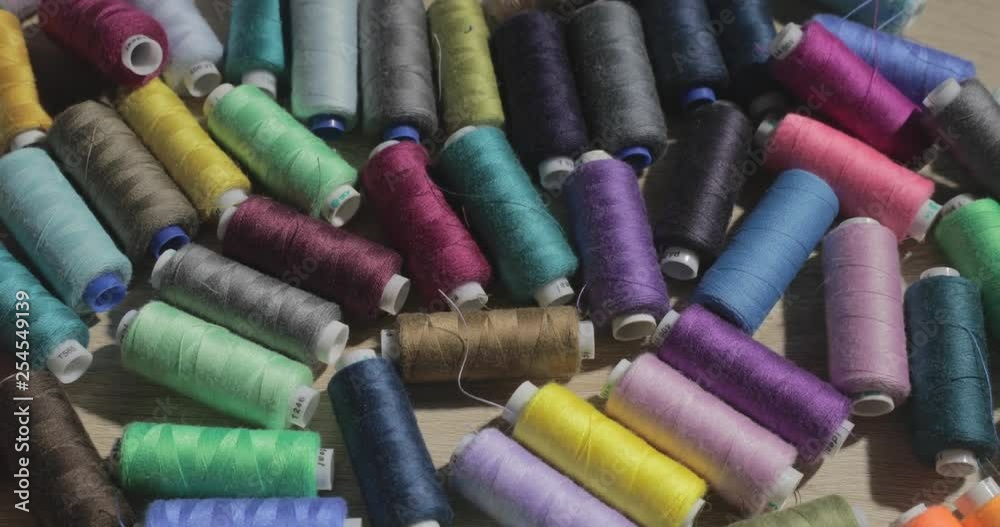 Slow motion video of rolls of strings of different color lie on a table, someone throws a roll of threads on a table Slow motion video of rolls of strings of different color lie on a table, someone throws a roll of threads on a table