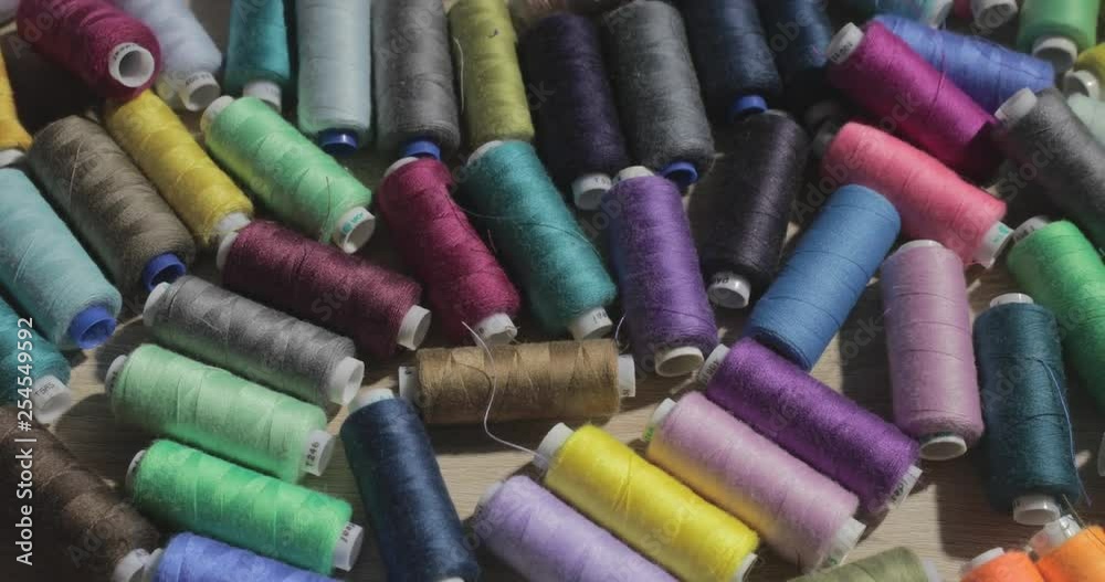 Slow motion video of rolls of strings of different color lie on a table, someone throws a roll of threads on a table Slow motion video of rolls of strings of different color lie on a table, someone throws a roll of threads on a table