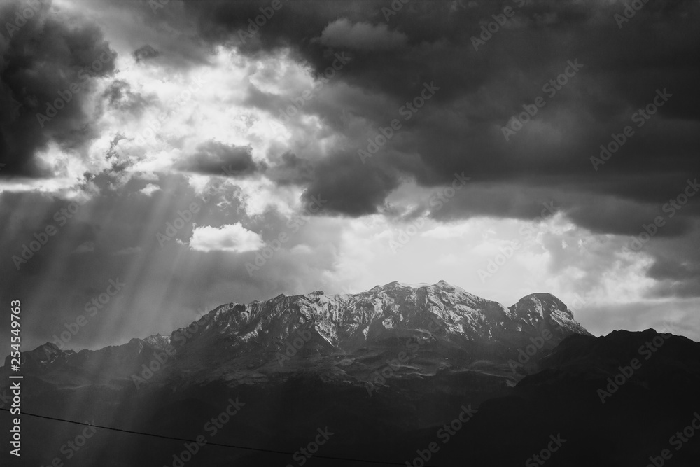 black and white photo of the iztaccihuatl summit covered by snow, ray of lights trough clouds