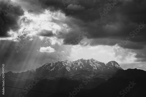 black and white photo of the iztaccihuatl summit covered by snow, ray of lights trough clouds photo