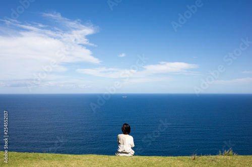 young girl sitting in front of the ocean