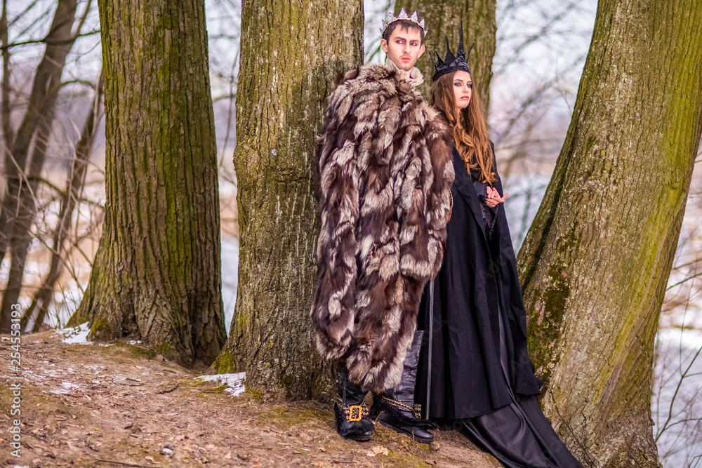 Art Photography and Cosplay.Caucasian Couple as King and Queen in Fur Medieval Outfit With Crowns Posing Together Outdoor. Art Photography and Cosplay.Caucasian Couple as King and Queen in Fur Medieval Outfit With Crowns Posing Together Outdoor.