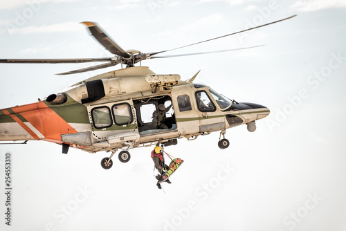 Rescue helicopter in flight winching rescuer photo