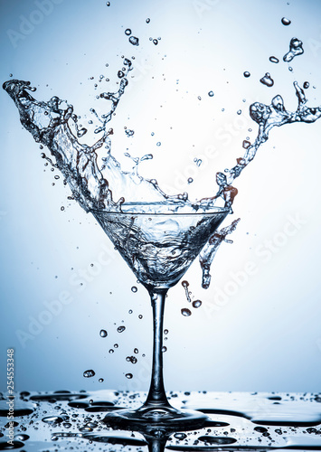 Water Splash Photography. Clear Wineglass With Burst of Water Splashes In Motion Against White Background.