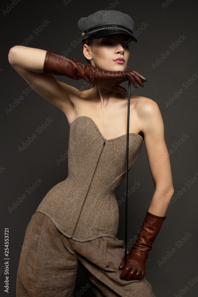 Studio portrait of beautiful woman in casual clothes. Young model wearing corset standing on grey background