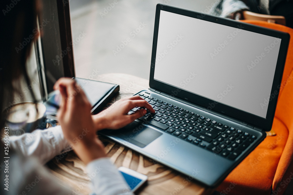 Side view of a woman sitting in a cafe while shopping online on a laptop. Side view of a woman sitting in a cafe while shopping online on a laptop.