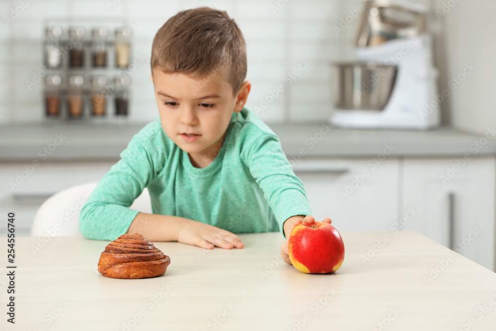 Fototapeta premium Little boy with pastry and apple at home. Diabetes diet